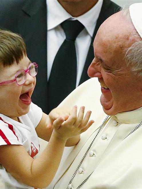 Pope Francis laughs with a child during a special audience  at the Vatican on Sunday. Photo by...