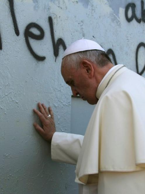 Pope Francis touches the wall that divides Israel from the West Bank, on his way to celebrate a...