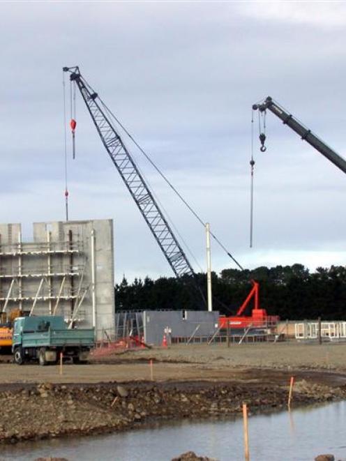 Precast concrete panels are craned into place for the walls for the drier at a new dairy plant at...