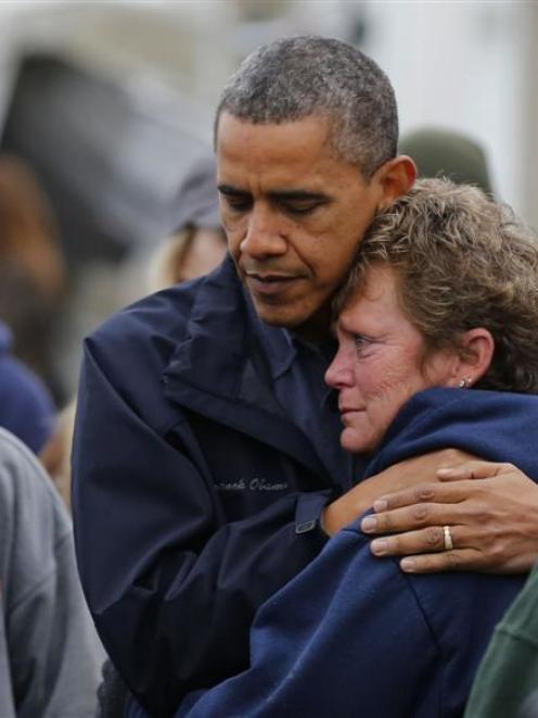 President Barack Obama hugs North Point Marina owner Donna Vanzant as he tours damage done by...