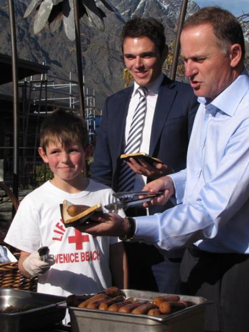 Prime Minister John Key hands out free sausages at Remarkables Park Town Centre yesterday with...