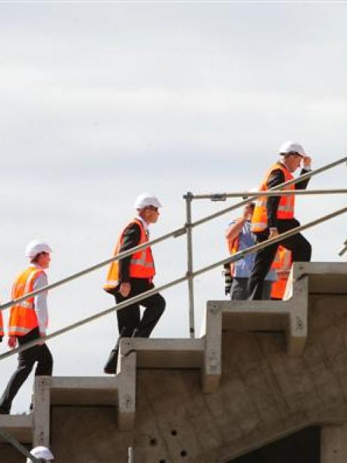 Prime Minister John Key (holding the peak of his hard hat) climbs to the top of the Forsyth Barr...
