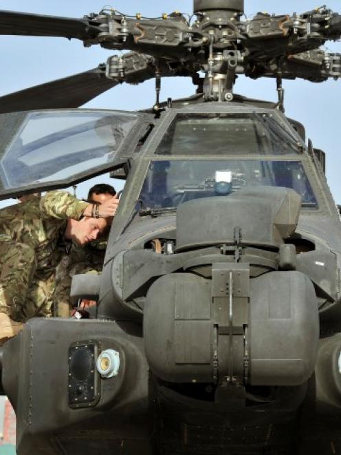 Prince Harry climbs up to examine the cockpit of an Apache helicopter at Camp Bastion in...