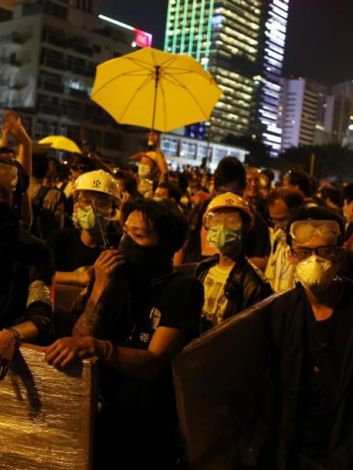 Pro-democracy protesters wearing goggles and masks block a road outside the chief executive...