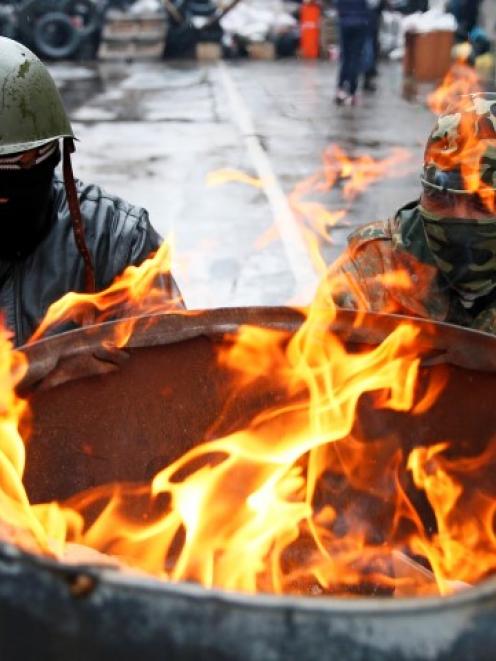 Pro-Russian men gather around a fire at a barricade near the police headquarters in Slaviansk,...