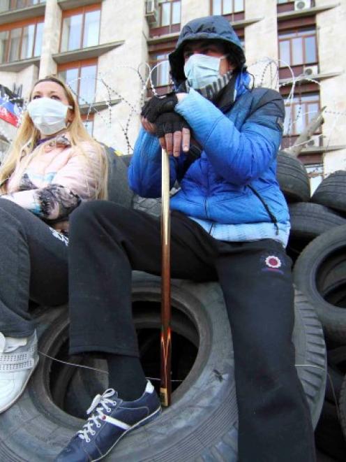 Pro-Russian protesters sit on automobile tyres outside a regional government building in Donetsk....
