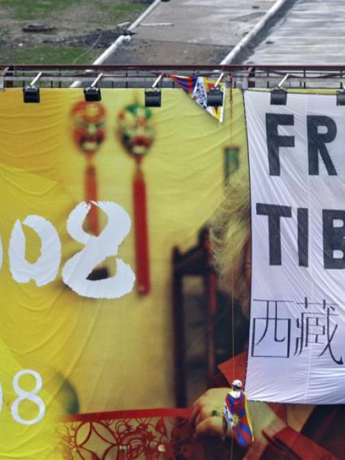 Pro Tibet activists unfurl a "Free Tibet" banner and Tibetan flags on top of a Beijing Olympics...