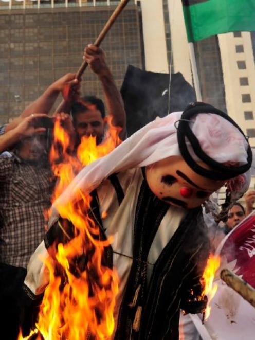 Protesters burn an effigy of Qatar's Emir Sheikh Hamad bin Khalifa al-Thaniat during a...