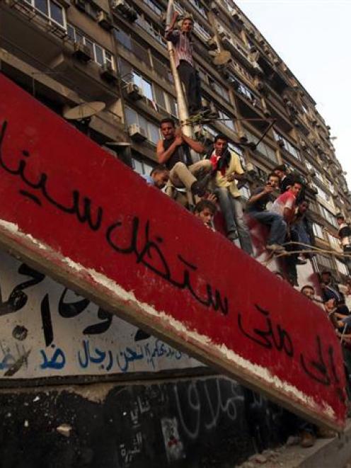 Protesters pull down part of a concrete wall built in front of the Israeli embassy in Cairo....