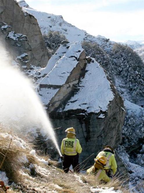 Queenstown Chief Fire Officer Bob Robertson (left) watches as firefighters pump water on the...