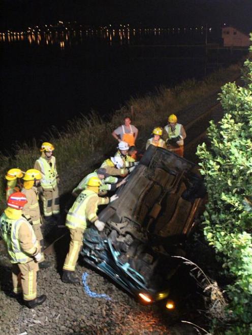 Ravensbourne Volunteer Fire Brigade members roll a car on to its wheels in Dunedin yesterday....