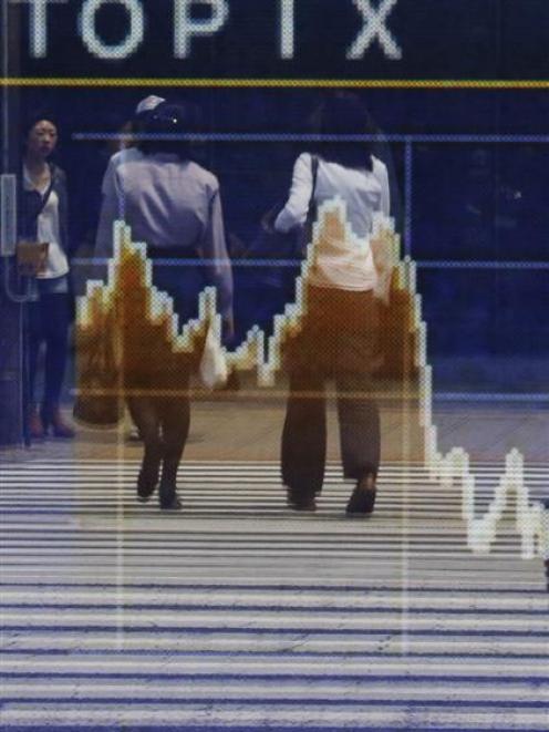 Reflections in a stock quotation board showing the falling Topix index outside a brokerage in...