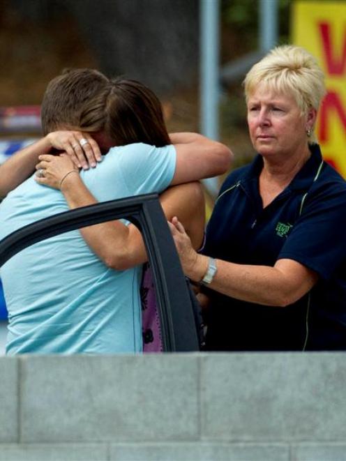 Relatives of a man who was attacked and killed by a shark at Muriwai Beach yesterday hug while...