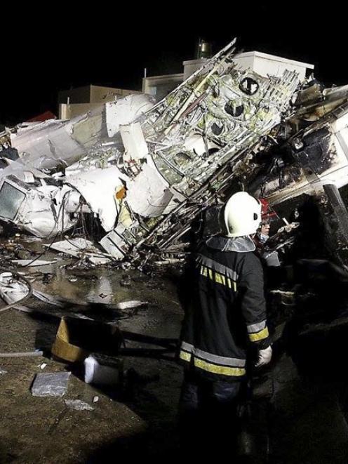 Rescue personnel survey the wreckage of TransAsia Airways flight GE222 on Taiwan's offshore...