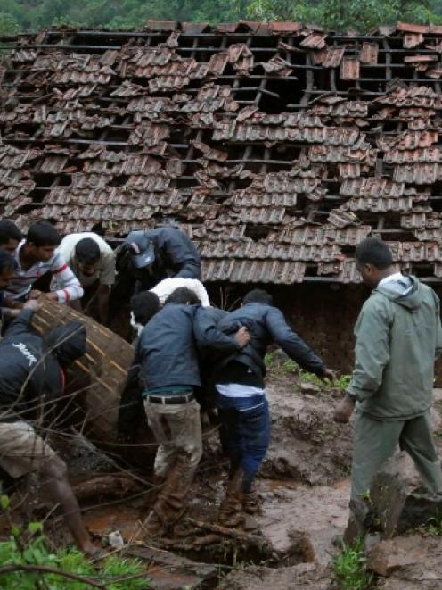 Rescue workers and volunteers clear the debris from the landslide site. REUTERS/Stringer