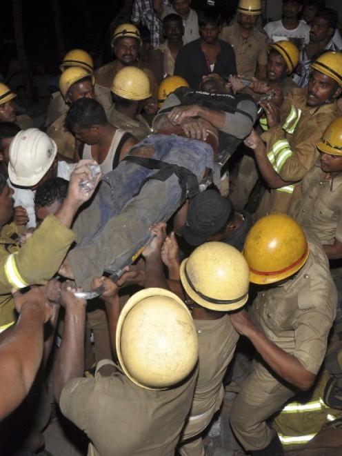 Rescue workers carry the body of an injured man at the site of a collapsed 11-storey building...