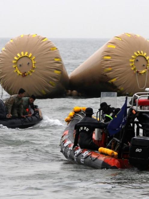 Rescue workers operate near floats where the capsized passenger ship Sewol sank in the sea off...
