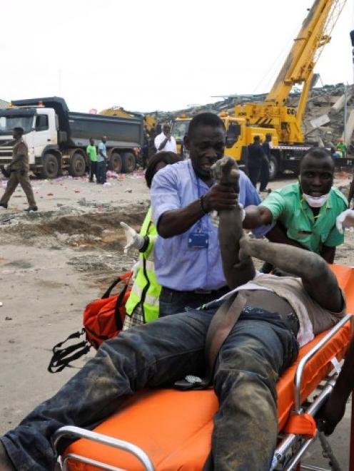 Rescue workers stretcher a wounded man out from the debris of a collapsed building in Accra,...