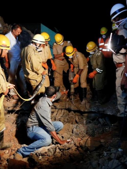 Rescue workers try to remove the body of a victim from the debris at the site of the collapsed...