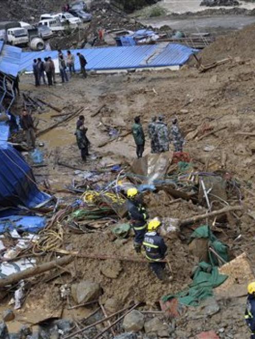 Rescuer workers at the site of a massive landslide triggered by heavy rain in Pengta Town,...
