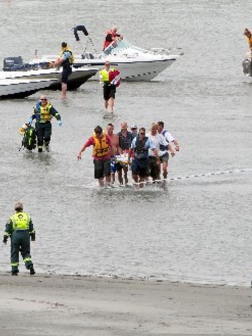 Rescuers carry an injured woman to a waiting helicopter as her partner and two children look on...