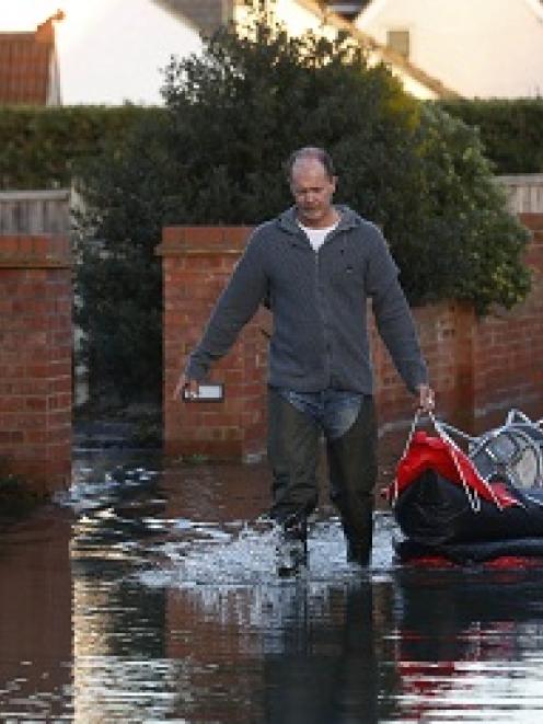 Residents bring back stools in a canoe to raise their furniture higher after the river Thames...