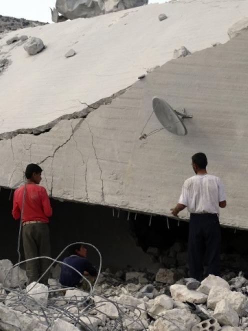 Residents inspect damaged buildings in what activists say was a US strike, in Kfredrian, Idlib...