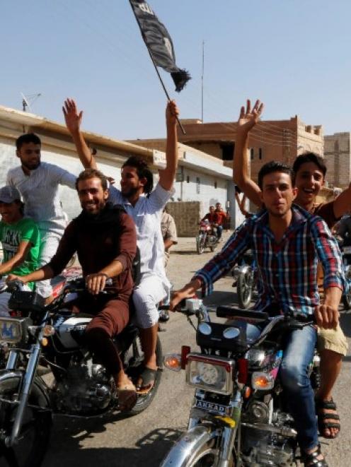 Residents of Tabqa city tour the streets on motorcycles, carrying flags in celebration after...