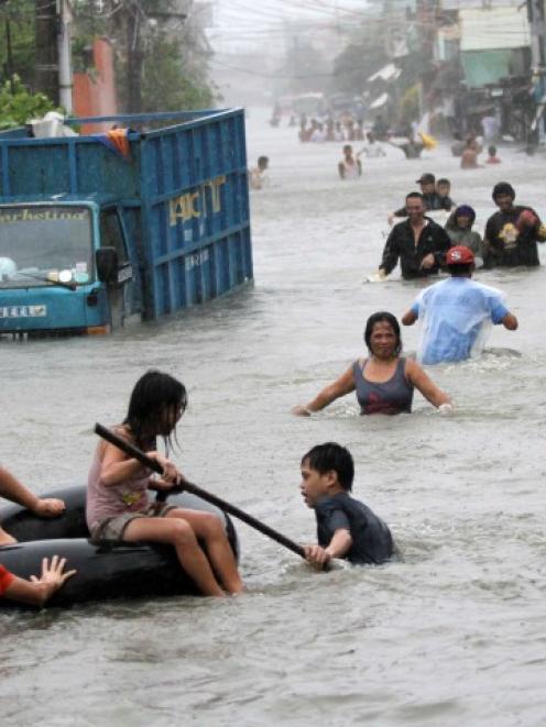 Residents wade through floodwaters brought by Typhoon Nesat in the Tanza town of Malabon city,...