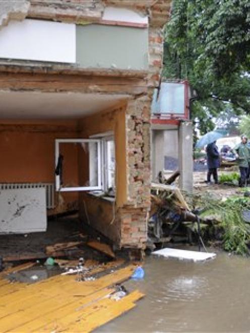 Residents walk among the debris following flooding in Bogatynia, Poland, on Saturday August 7,...