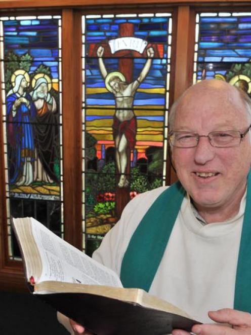 Reverend Stephen White  in front of the stained glass windows at St  Luke's  on the  Taieri....