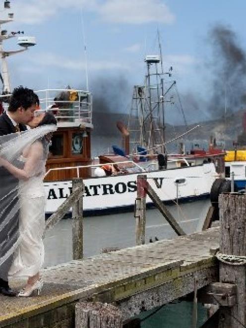 Rob Ong kisses his bride May Eng on Careys Bay wharf on Monday afternoon, just as a large fire...