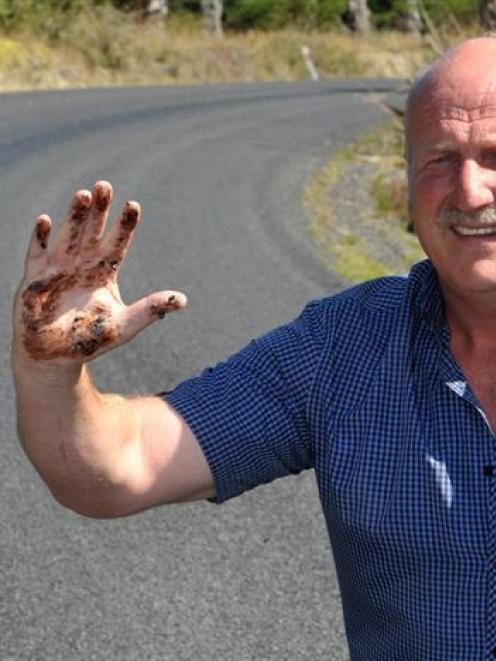 Robert Scott inspects melted tar and loose aggregate on Saddle Hill Rd.  Photo by Christine O...