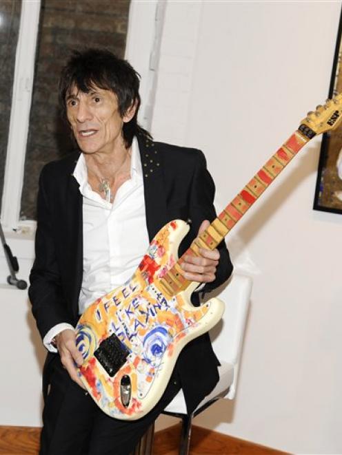 Rolling Stones guitarist Ronnie Wood holds up one of his works of art during a news conference...