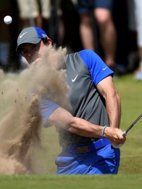 Rory McIlroy hits from a bunker on the 16th hole during the first round of the British Open....