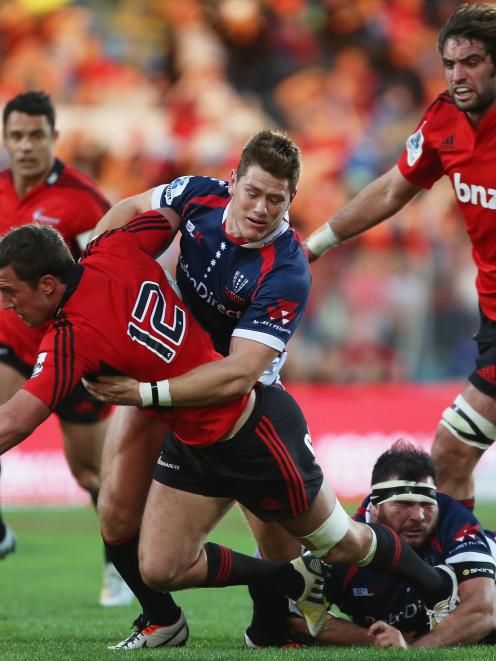 Rory Sidey and Laurie Weeks of the Rebels tackle Tom Taylor of the Crusaders. (Photo by Joseph...