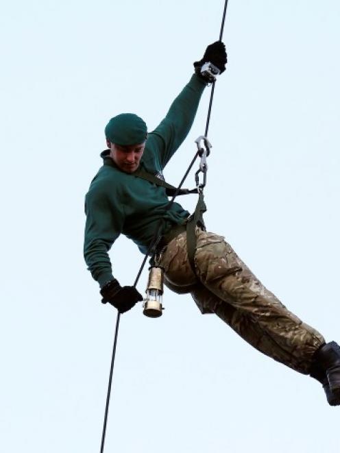 Royal Marine Martyn Williams carries the London 2012 Olympic flame inside a lantern as he abseils...
