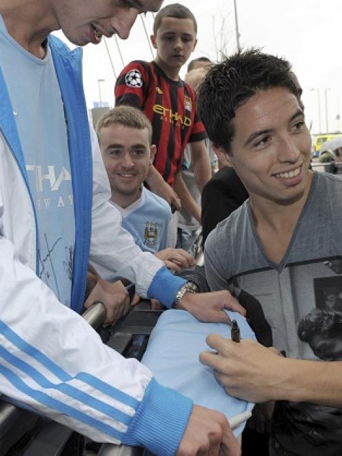 Samir Nasri signs autographs as he is greeted by fans outside Manchester City's Etihad Stadium in...