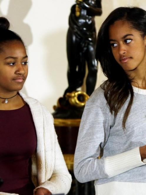 Sasha (L) and Malia Obama listen to their father during the pardoning of the National...