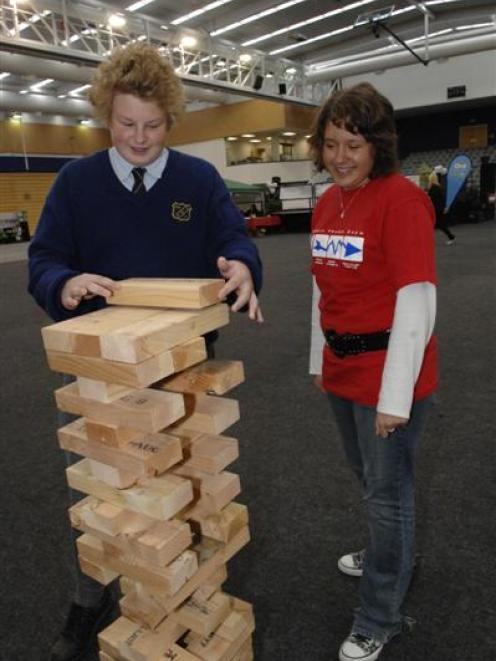 Tokomairiro High School pupil Tony Powick (15) moves a supersize "Jenga" block, watched by Queens...