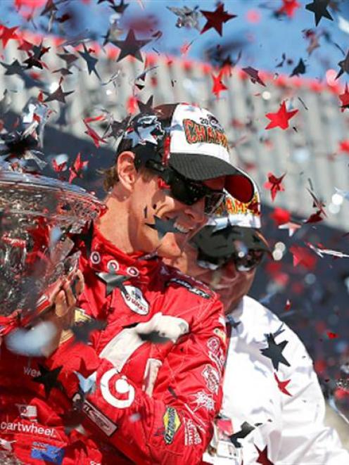 Scott Dixon celebrates on the podium after winning the IndyCar championship.