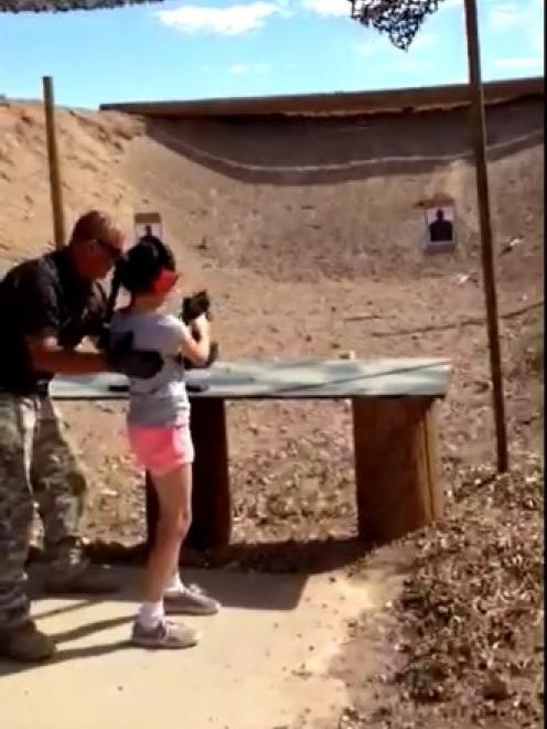 Shooting instructor Charles Vacca stands next to a 9-year-old girl at the Last Stop shooting...