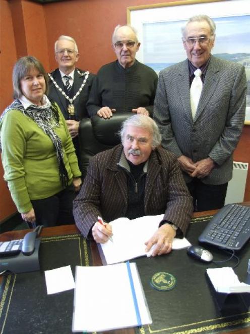Signing a trust deed this week are Hearts and Hands for Haiti trustees Bruce Albiston (seated,...