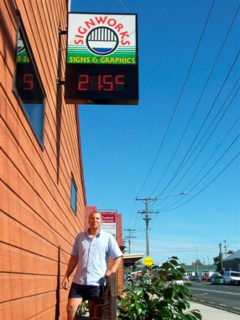 Signworks installer Peter Gray  stands under the new digital clock and temperature gauge...