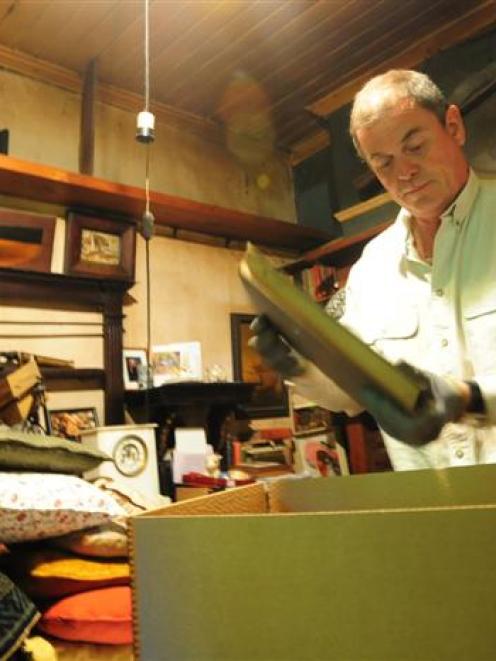 Simon Knight fills cardboard boxes with his father's collections. Photo by Craig Baxter.