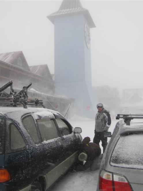 Skiers at Cardrona Ski Area  fit chains to their vehicles for the journey down the mountain as a...