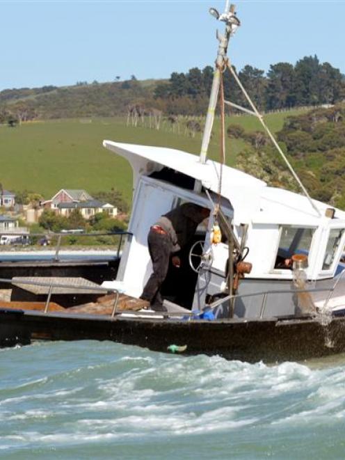Skipper Colin Webb tosses a pot of water out the wheelhouse window in an attempt to refloat the...