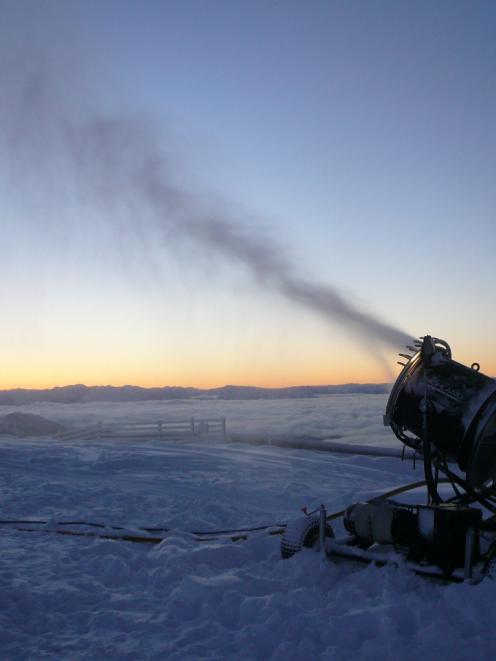 A snowgun at Treble Cone pumps out the artificial white stuff yesterday at dawn, as a layer of...