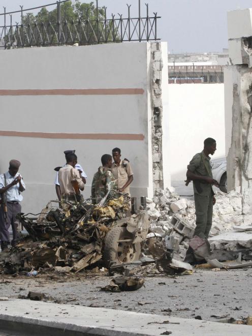 Somali government forces assess the scene of a suicide car explosion in front of the SYL hotel in...