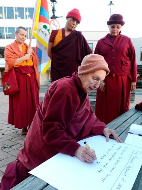 Sonam Chokyi writes a translation of a message of protest from Geshe Jampa Tenzin (back, centre)...